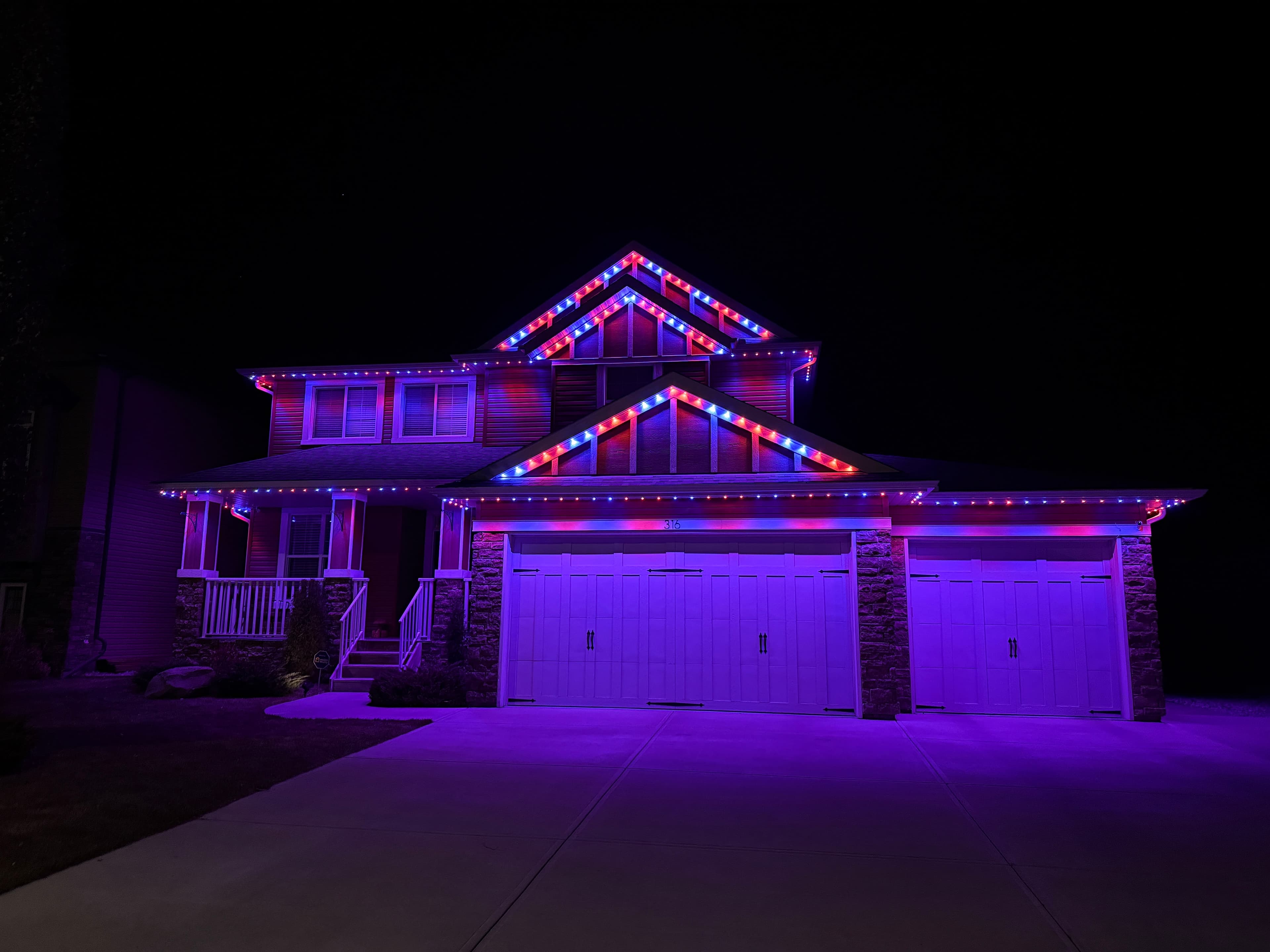 Permanent lights installed on a home at night with warm white glow