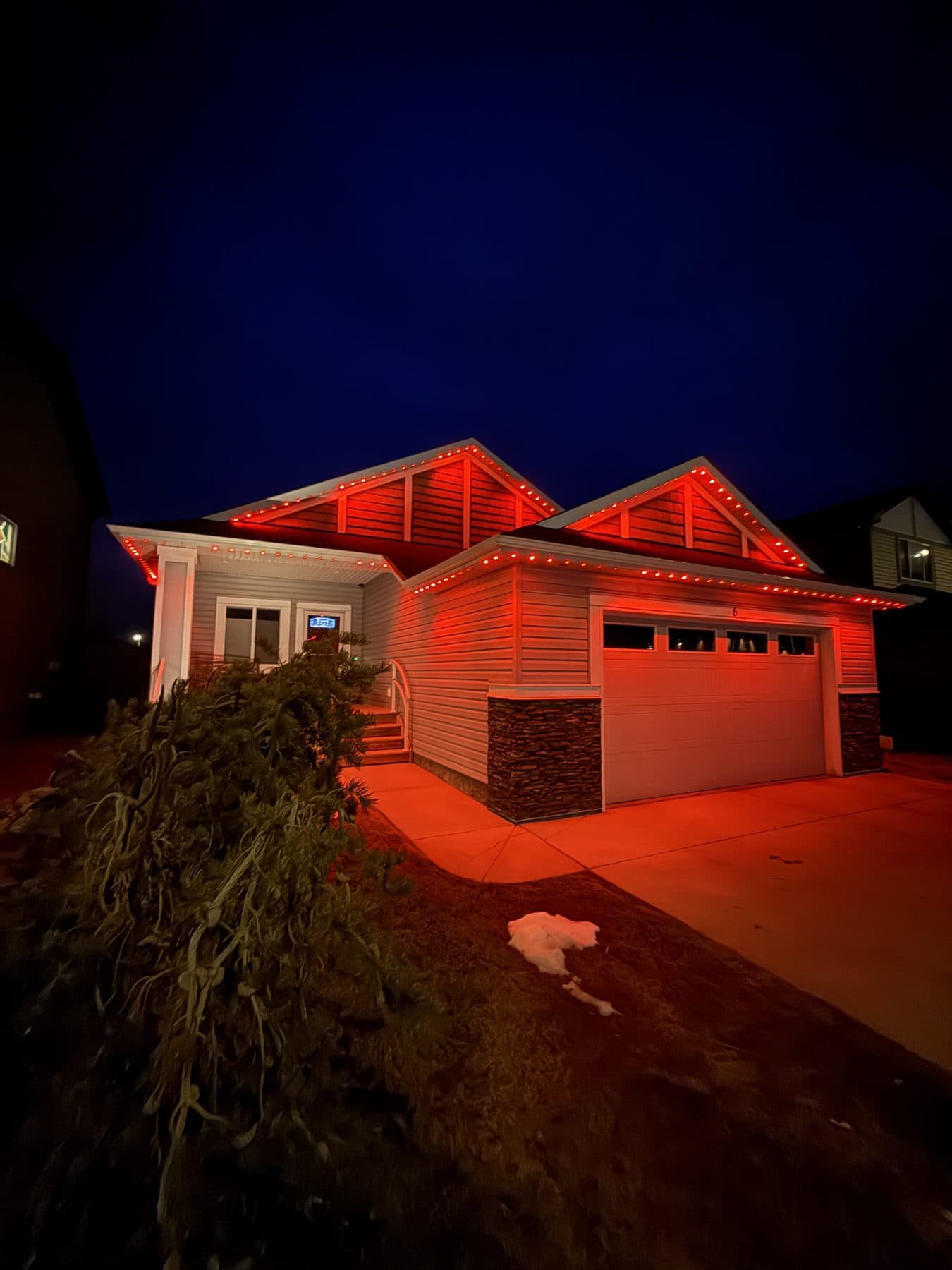 Permanent LED lights on a Calgary home showing a red scene across the roofline and both gable peaks