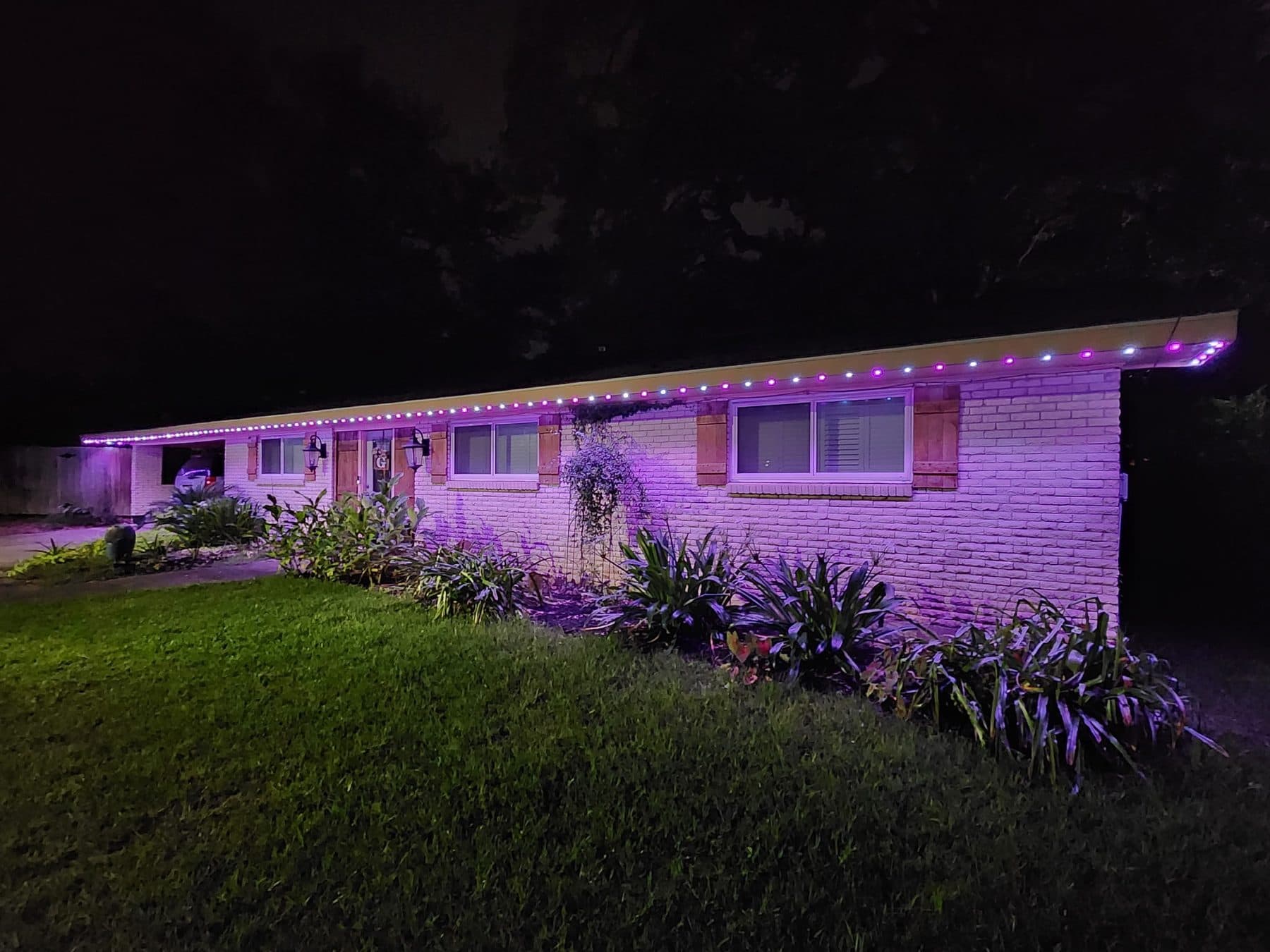 Permanent LED lights running a multi-colour pattern along the roofline of a Lake Charles home at night