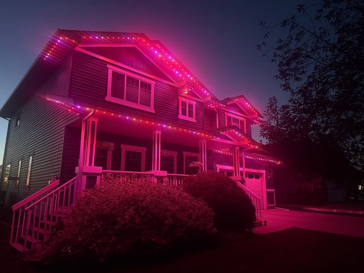 Calgary home glowing with warm white permanent LED lights along the roofline at dusk