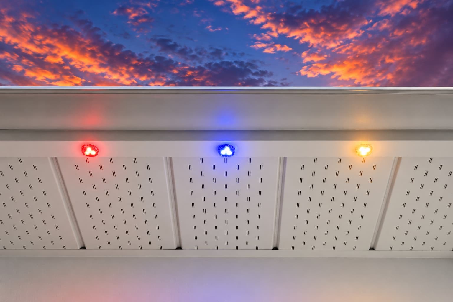 RGBW pucks glowing under a soffit at twilight