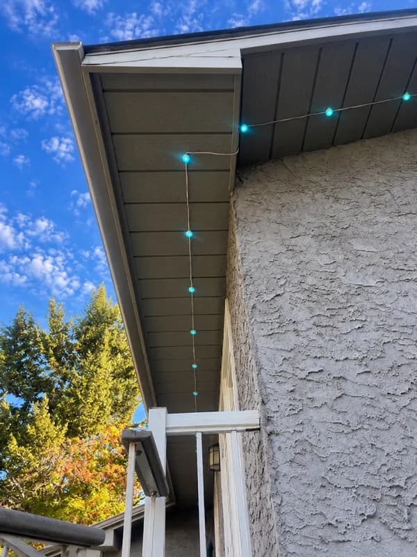 String lights on a visible wire under an eave