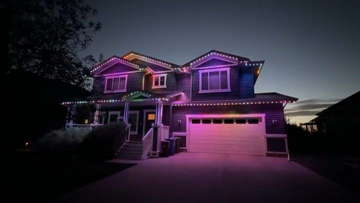 Okotoks two-storey home at night with colour-changing permanent lights along the soffits