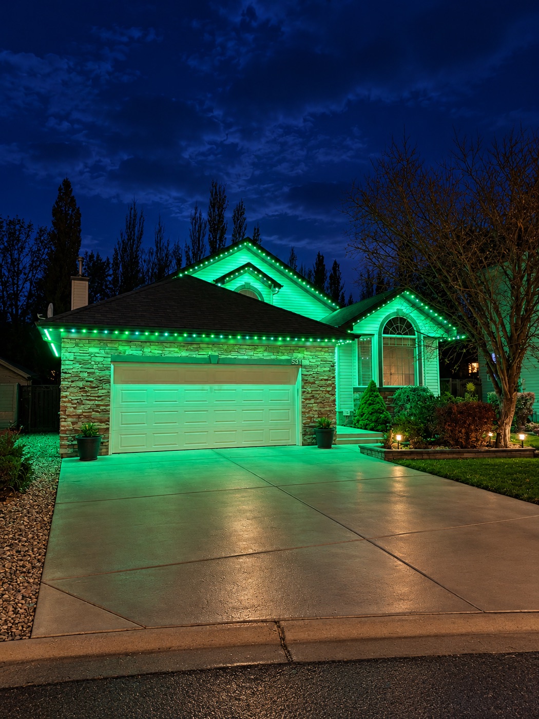 Bungalow at night with green permanent lights along the roofline and gables