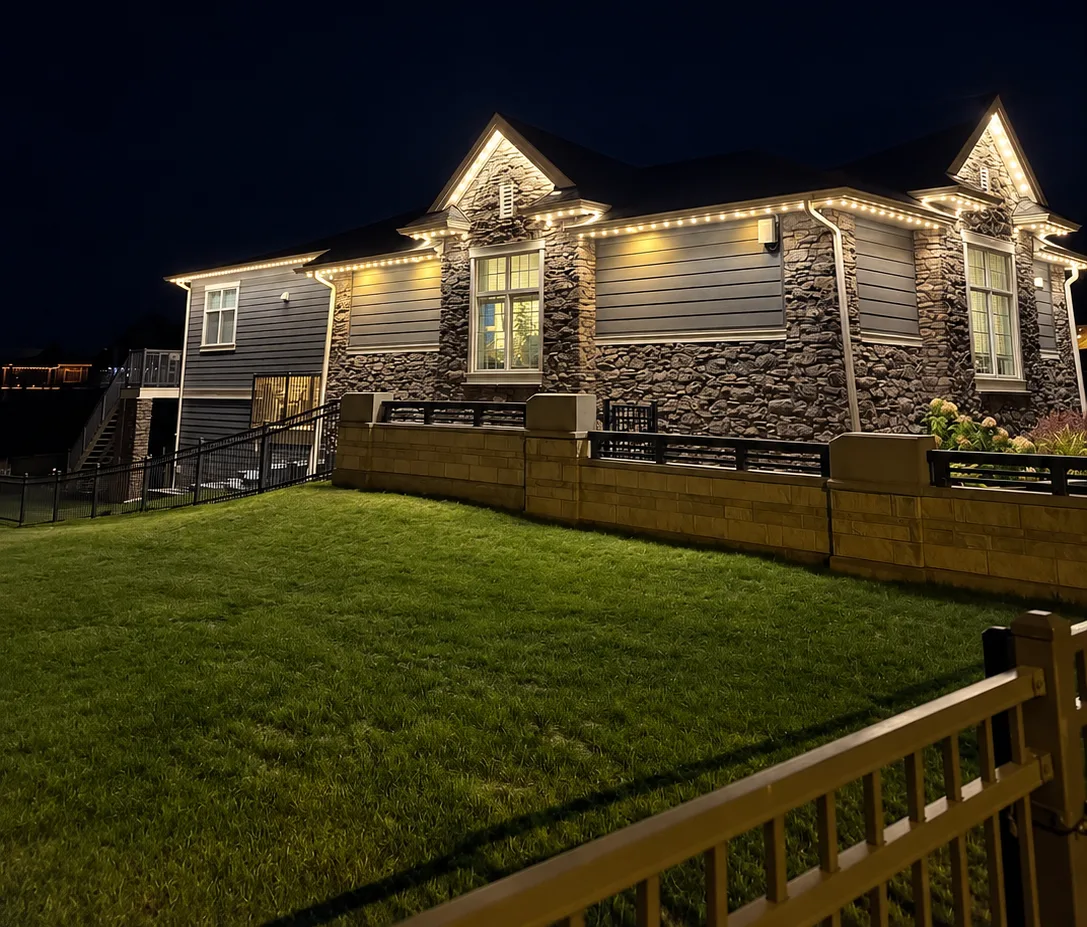 Wide night view of a home with permanent lights tracing every roofline and gable